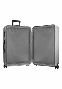 Valise rigide argentée avec quincaillerie noire, double compartiments, séparateurs en maille et une poignée rétractable. Quatre roues pour faciliter la mobilité.