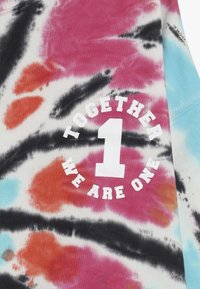 Top tank w stylu tie-dye w żywymi wzorami w kolorach różowym, czarnym i pomarańczowym. Na przodzie znajduje się napis "RAZEM JEDNO JESTEŚMY" w białym kolorze.