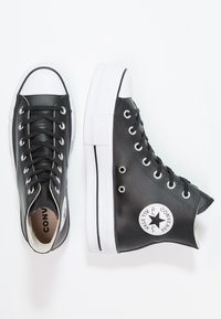  svarte høy-top sneakers laget av lær med hvit gummisåle. Funksjoner inkluderer kontrasterende hvit tåhette og snøringer, samt logopatch på ankelen.