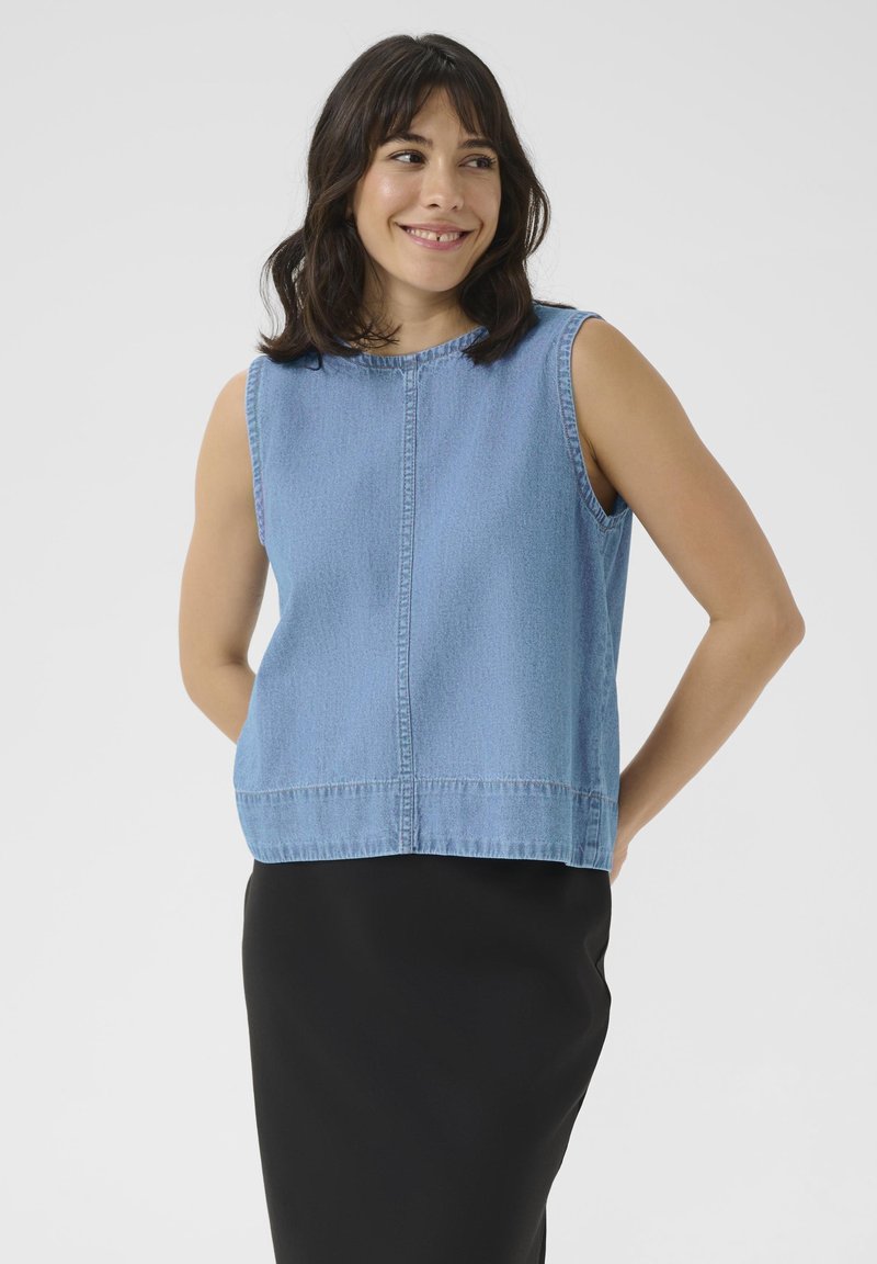 Light blue denim sleeveless top with a round neckline, straight cut, and visible seams. Worn over a black skirt. Simple and casual design.