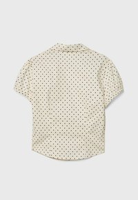 Short-sleeved blouse in cream fabric with black polka dots, featuring a classic collar and gathered details at the sleeves, smooth texture.