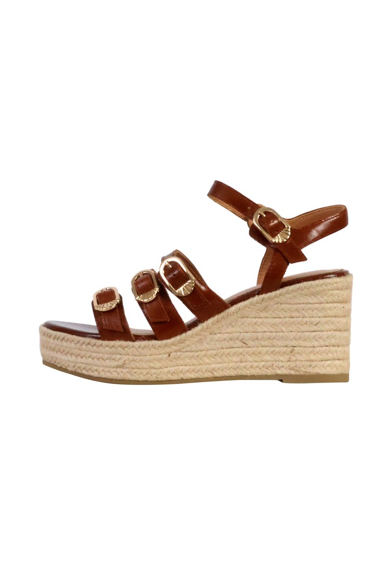 Sandale compensée en cuir marron avec trois sangles réglables, boucles dorées et un talon enroulé de jute. La semelle est plate et texturée pour une meilleure adhérence.