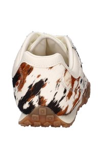 Sneaker met een witte leren basis, voorzien van een bruin en zwart koeienhuidprint. Textuur oppervlak, solide rubberen zool met kleine gripnopjes.