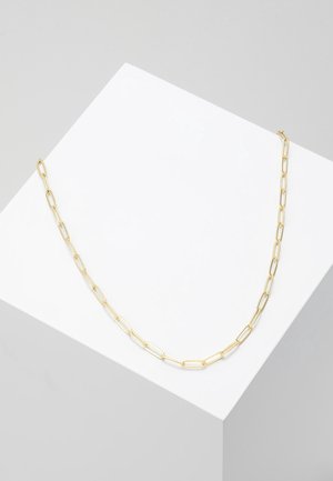 Collier délicat en chaîne d'or avec des maillons ovales allongés présenté sur une surface blanche inclinée sur un fond gris clair.