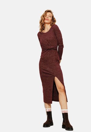 Robe longue bourgogne en tissu côtelé, dotée de manches longues, d'une taille à nouer et d'une fente sur le côté, associée à des bottines cheville marron foncé.