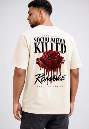 Mann trägt ein weißes T-Shirt mit einer tropfenden roten Rose und dem Text "Soziale Medien haben die Romantik getötet, folge mir nicht" auf dem Rücken.
