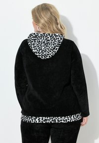 Sort fleece hættetrøje med leopardprintet for i hætten. Blød tekstur, lidt længere bagpå, og matchende leopardprintdetalje ved kanten.