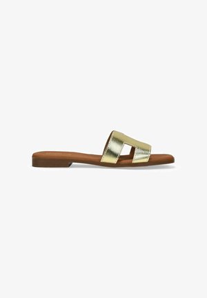 Sandalia plana de metal dorado con dos correas anchas y una suela marrón. La parte superior presenta una textura suave y detalles de corte.