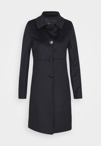 Manteau noir longueur genou avec manches longues, col classique et quatre boutons sur le devant sur un fond clair uni.