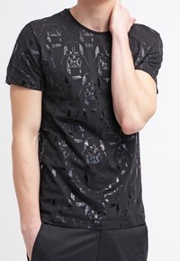 Černé bavlněné tričko s potiskem Darth Vadera po celém povrchu v různých odstínech, kulatým výstřihem a krátkými rukávy. Hladká textura.