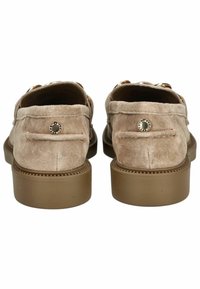 Mocasines de ante en color beige claro con suelas de goma marrón. Presentan costuras decorativas y un acento metálico redondo en el talón.