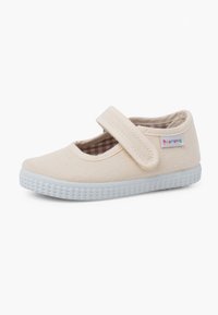 Scarpa Mary Jane in tela beige con una cintura in velcro, suola in gomma leggera e un motivo interno a scacchi. Presenta una piccola etichetta di marca.