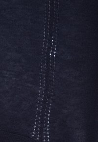 Dunkelblauer Strickstoff mit zwei vertikalen Reihen von kleinen, gleichmäßig verteilten, weißen Punktakzenten entlang der Mitte, mit einer weichen Textur.