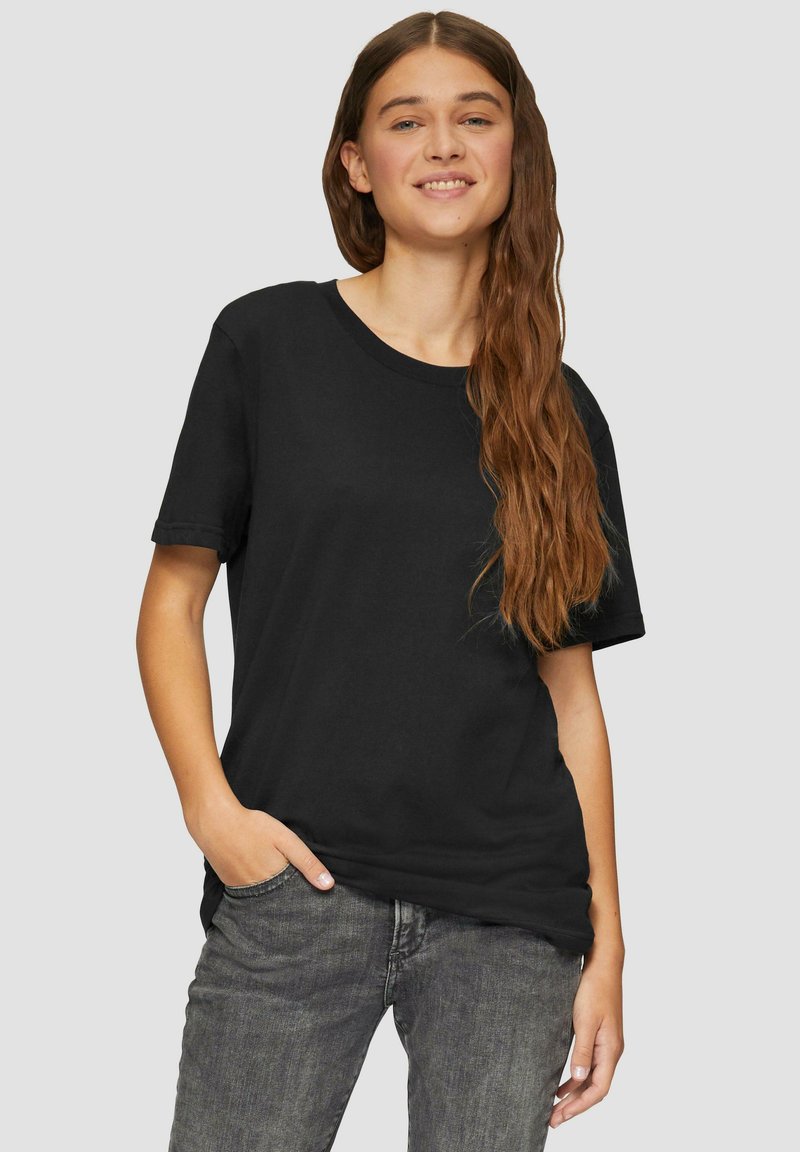 Zwarte katoenen T-shirt met een relaxte pasvorm, korte mouwen en een ronde halslijn, gecombineerd met grijze jeans. Geen zichtbare patronen of accenten.