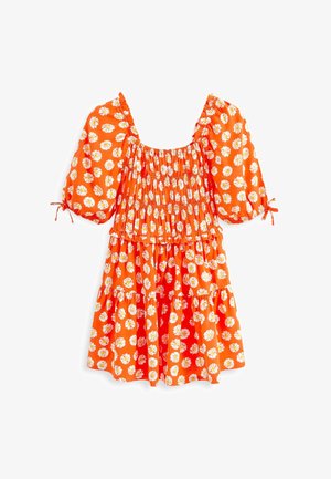 Robe courte orange avec manches bouffantes, imprimé floral de marguerites blanches, corsage froncé et jupe à volants froncée.