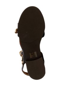 Sandale noire avec une semelle texturée, dotée d'un détail de boucle dorée et d'un petit talon. Le coussin de pied est marron, avec une finition lisse.