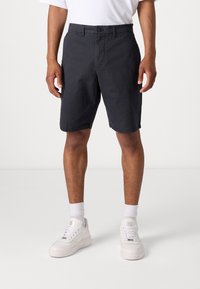 Dark gray shorts made of cotton, featuring a flat front, button closure, and side pockets. Worn with white athletic shoes and socks.