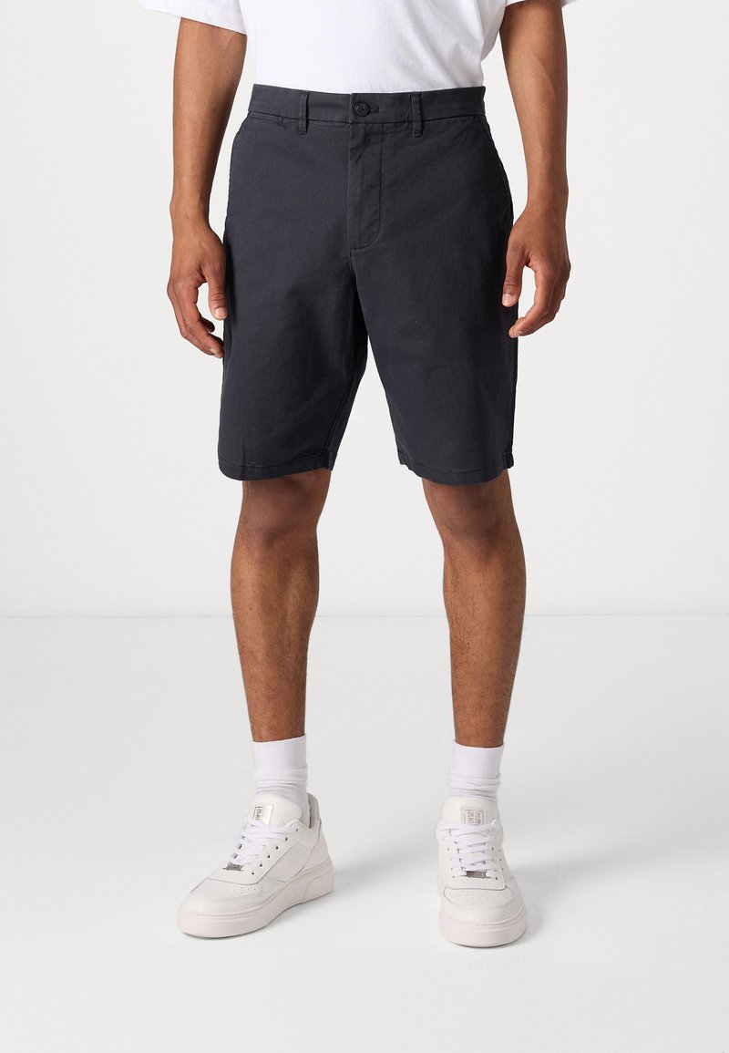 Dark gray shorts made of cotton, featuring a flat front, button closure, and side pockets. Worn with white athletic shoes and socks.