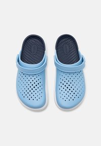Blue plastic clogs with perforated design, white sole, and navy blue interior. Features adjustable strap for secure fit.