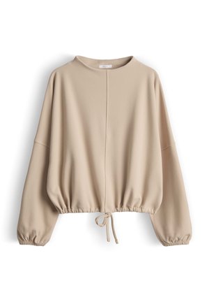 Haut beige à manches longues en tissu doux. Présente un col montant, un ourlet froncé avec cordon de serrage, et une coupe décontractée. Texture lisse.