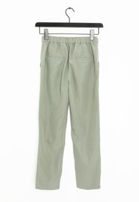 Un pantalon vert clair avec une taille élastique, deux poches arrière et une coupe droite, suspendu à un cintre noir sur un fond blanc.