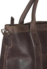 Brązowa skórzana torebka z teksturowaną powierzchnią, podwójnymi mocnymi uchwytami oraz kontrastowym przeszyciem z metalowym detalem w formie pierścienia.