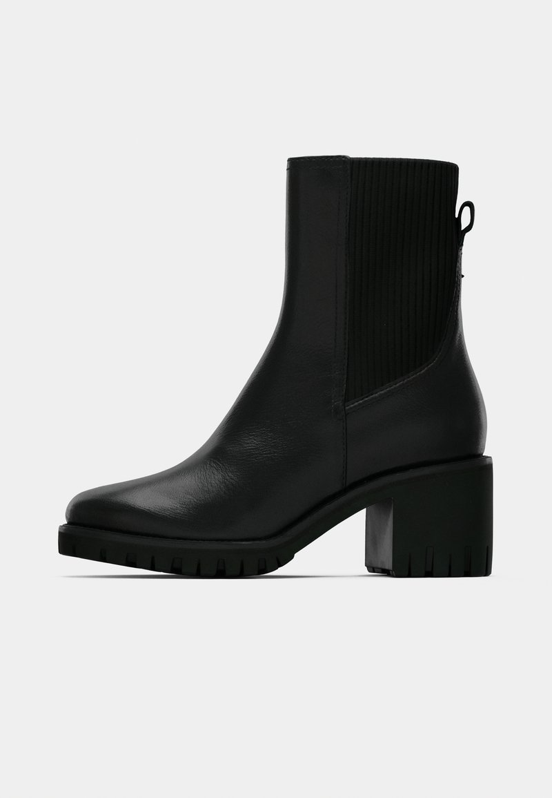 Μαύρο δερμάτινο μποτάκι αστραγάλου με πλευρική ραβδωτή ελαστική επένδυση, τακούνι σε μπλοκ και υφασμένο πάτο για πρόσφυση. Λείο φινίρισμα με ελάχιστο μεταλλικό εξοπλισμό.