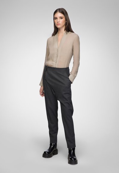 Beige sheer blouse with buttons, paired with high-waisted, dark gray tapered trousers and chunky black boots. Minimalist design and textures.