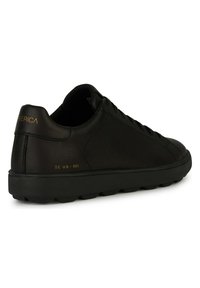 Svart lädersneaker med en slät finish, rund tå och platt sula. Har guldbranding på hälen och en minimalistisk snörningsdesign.