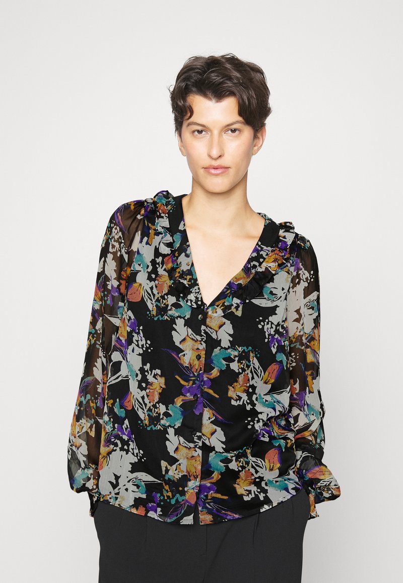 Blusa preta com padrão floral, apresentando um decote com babados, mangas longas transparentes, e padrões florais coloridos em roxo, laranja e azul-turquesa sobre um fundo escuro.