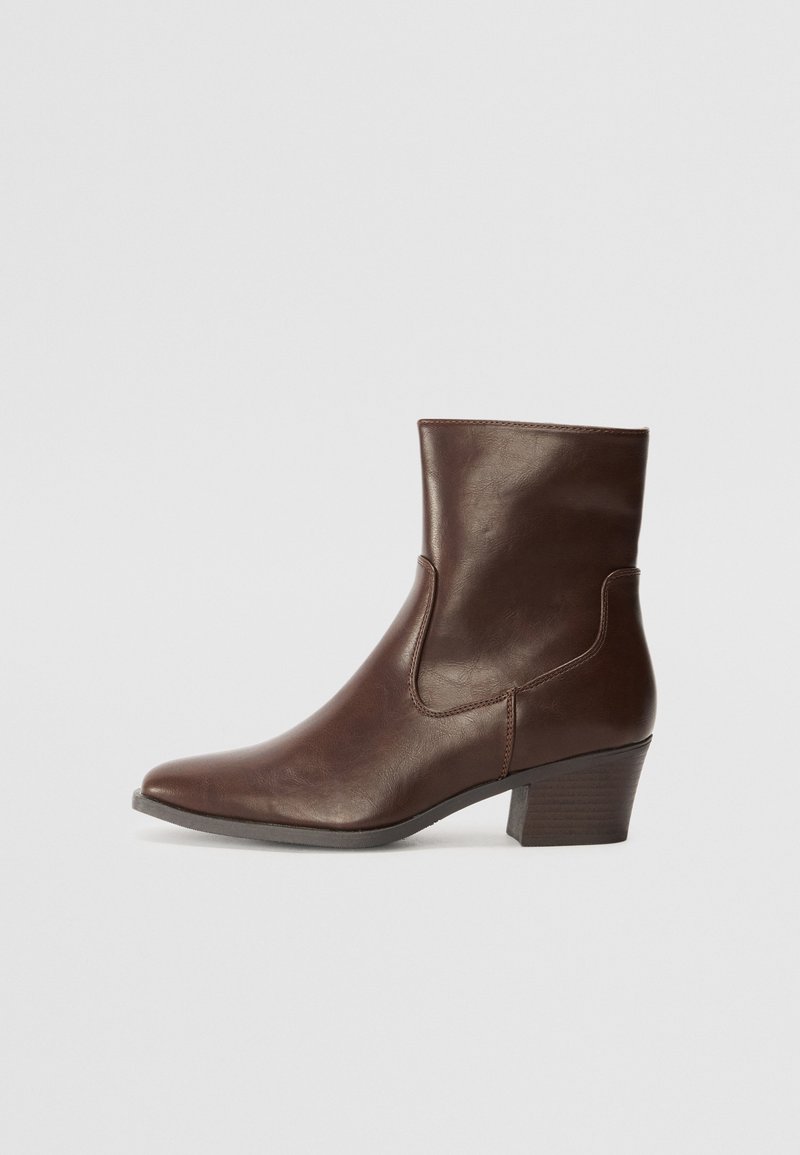 Brown leather ankle boot with a pointed toe and a block heel. Features side cutouts and a smooth texture, designed for a fitted silhouette.