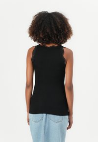 Sort med ermene ribbet topp som har blondedetaljer på skuldrene, tettsittende design og en glatt tekstur, parret med et lyst denimskjørt.