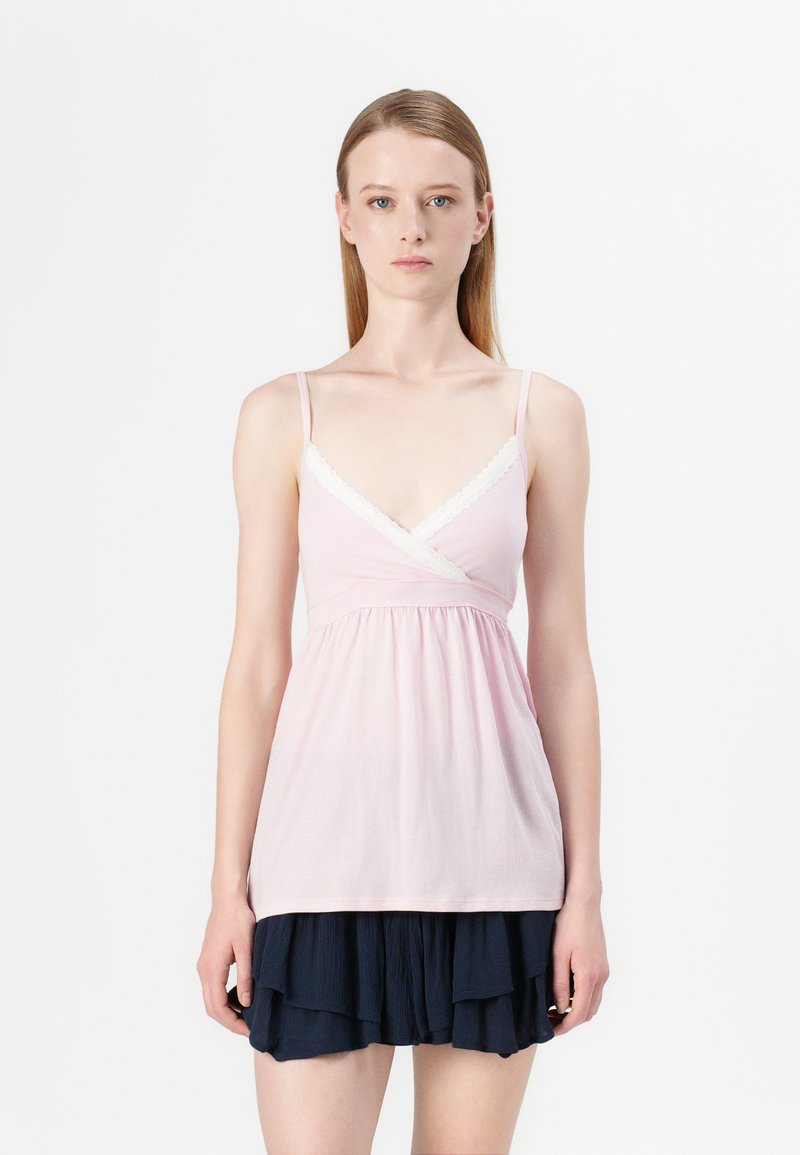 Pink sleeveless top with a v-neck, lace trim, gathered waist, layered navy skirt with ruffles, smooth fabric texture.