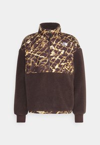 Polarfleece pullover met een bovenstuk in bruin en gouden dierenprint en een effen donkerbruine onderzijde. Kwart rits sluiting en staande kraag.