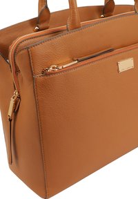 Bruine leren handtas met een gestructureerde afwerking, voorzien van dubbele handvatten aan de bovenkant, goudkleurige hardware en een voorvak met rits.