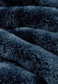 Námornícky modrý plyšový prikrývka s mäkkou, hustou kožušinou, s vlnitými záhybmi a rôznou výškou hromady pre útulný vzhľad.