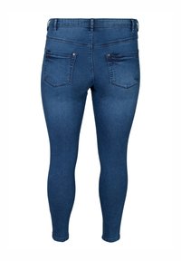 Jeans skinny en denim bleu foncé. Caractéristiques : taille mi-haute, design à cinq poches avec deux poches arrière, et une finition lisse et texturée.