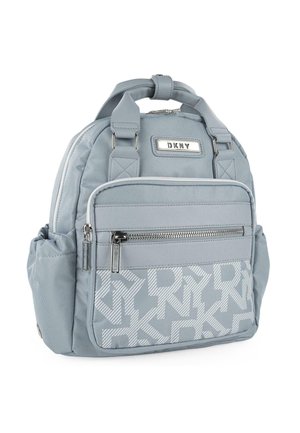 Mochila azul clara con un acabado texturizado, que cuenta con un bolsillo frontal con cremallera y un patrón de logotipos repetido. Incluye correas ajustables.