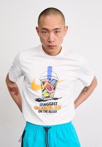 Hvid bomulds t-shirt med et farverigt bubble tea grafik med et blåt sugerør og teksten "De Største Bobler i Kvarteret."