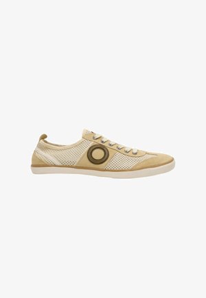 Zapatilla casual beige de caña baja con laterales perforados, cierre de cordones en la parte delantera y detalle circular de parche de ante en el lateral exterior.