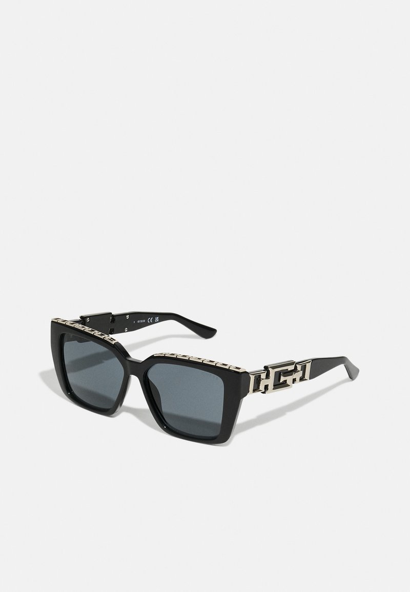 Black rectangular sunglasses with dark lenses and a thick frame. The sides feature a metallic chain design with gold accents.