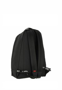 Mochila de poliéster negra con dos correas acolchadas, forma rectangular, textura sutil y una correa ajustable de marca en la base.