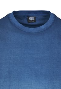 Zila kokvilnas t-kreklis ar apaļu apkakli, kuram ir gluda tekstūra un maigs gradients. Etiķete norāda "Urban Classics," izmērs M.