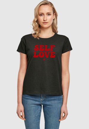Sort bomulds t-shirt med rød tekst, der står "SELVELSKER" med et hjerte som accent, rund halsudskæring og korte ærmer.