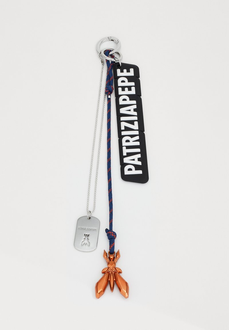 Sleutelhangeraccessoire met een zilveren dogtag, multicolore gevlochten band en een oranje metalen charme in de vorm van een insect.