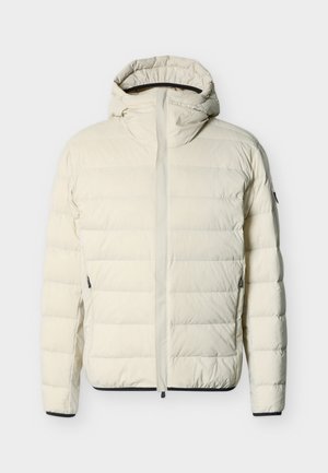 Kremenasto barvana prešita puhovka z pripeto kapuco, sprednjo zadrgo, z zadrgami na stranskih žepih ter črnim obrobom na manšetah in spodnjem robu.