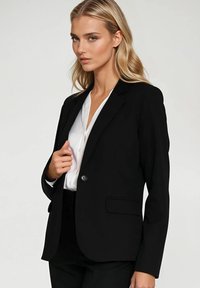 Czarna marynarka o dopasowanym kroju, zapinana na jeden guzik, z wyłogami i gładką teksturą, zestawiona z białą bluzką pod spodem.