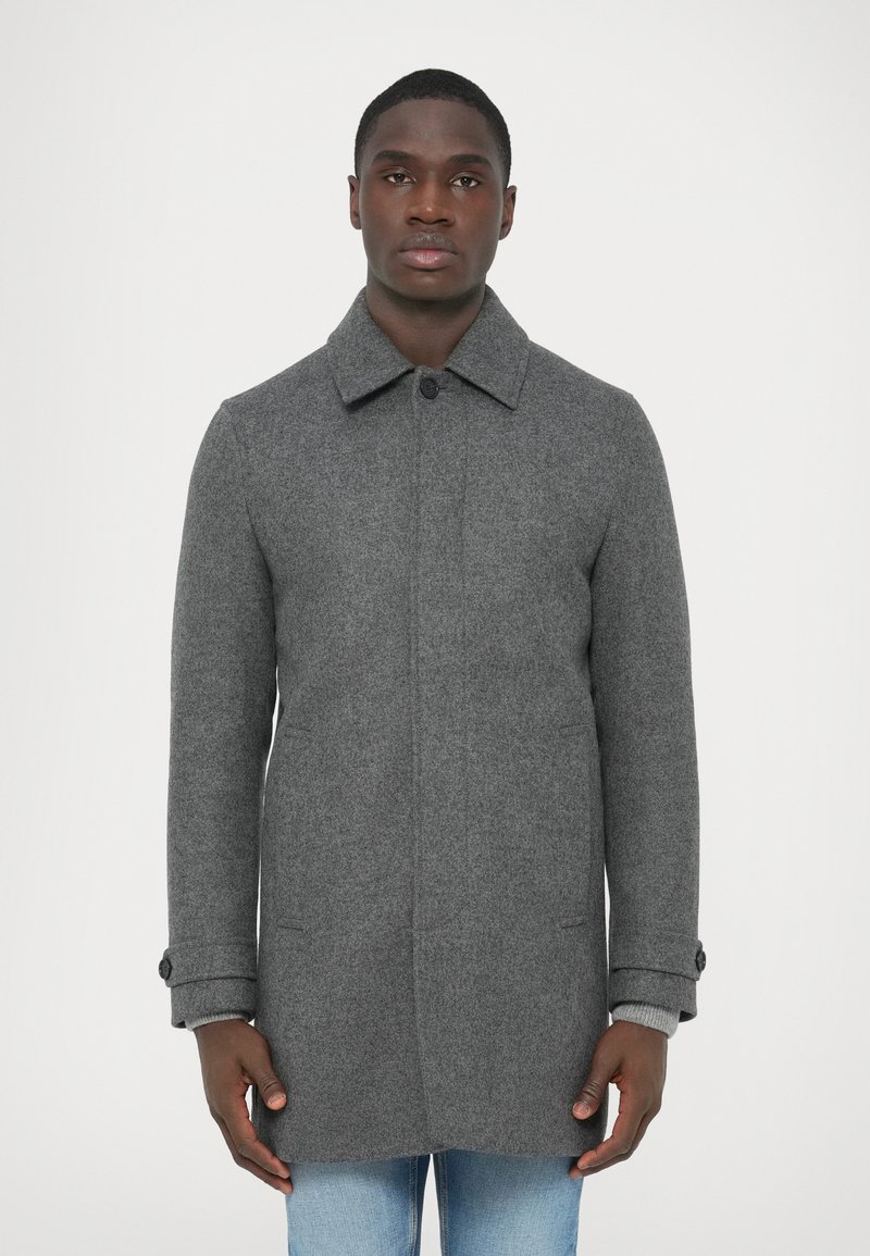 Γκρι μάλλινο παλτό με γιακά στο λαιμό, κούμπωμα μ�ε κουμπιά στο μπροστινό μέρος, πλαϊνές τσέπες και λεπτομέρειες στα μανίκια. Λείο υλικό με εφαρμοστή γραμμή.
