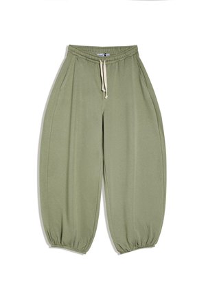 Pantalon de survêtement vert olive ample avec taille élastique et cordon blanc, poches latérales, et poignets élastiques aux chevilles.