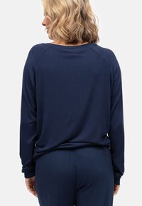 Marineblauwe longsleeve top met een ontspannen pasvorm, ronde halslijn en geribde manchetten, gecombineerd met bijpassende onderkant in zachte, gladde stof.